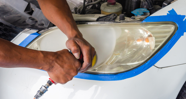 The start of headlight restoration an employee polishing out the cloudy layer of plastic