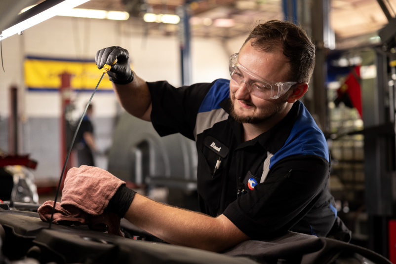 Employee using an oil dip stick