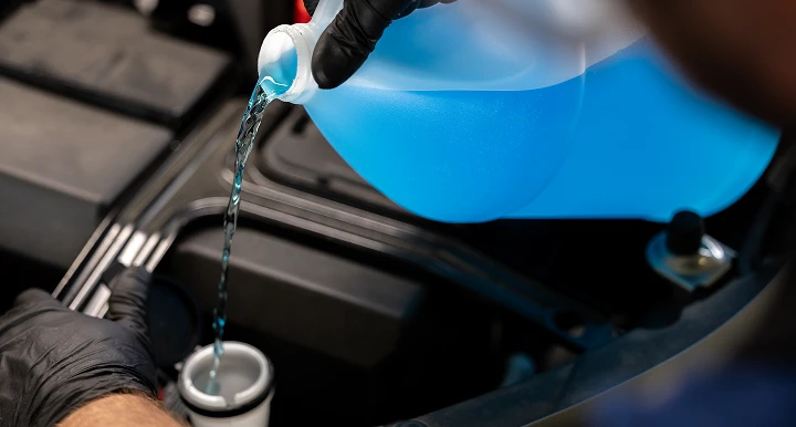 man pouring washer fluid into a car